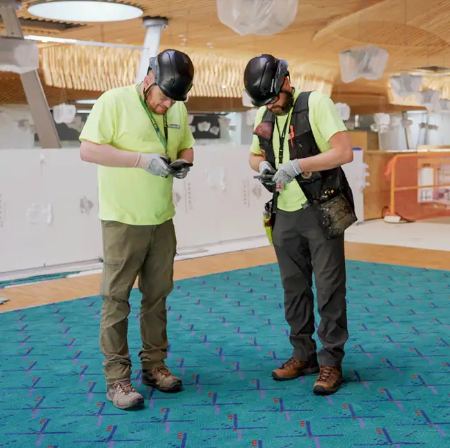 two men in hardhats taking shoe selfies