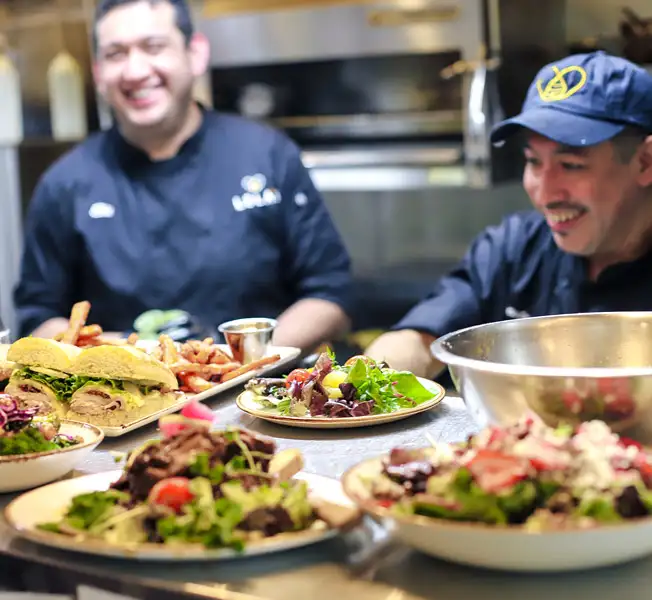 men serving up salads and sandwiches