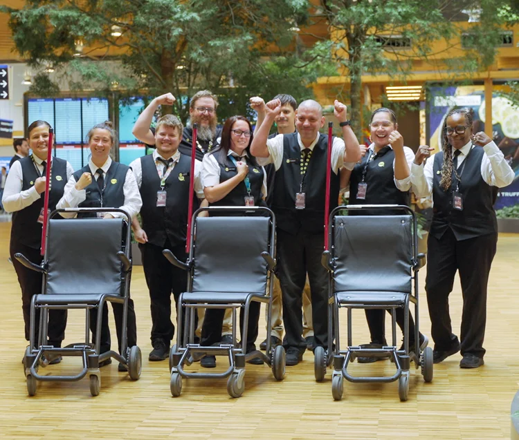 a group of wheelchair assistance providers raise their hands in celebration