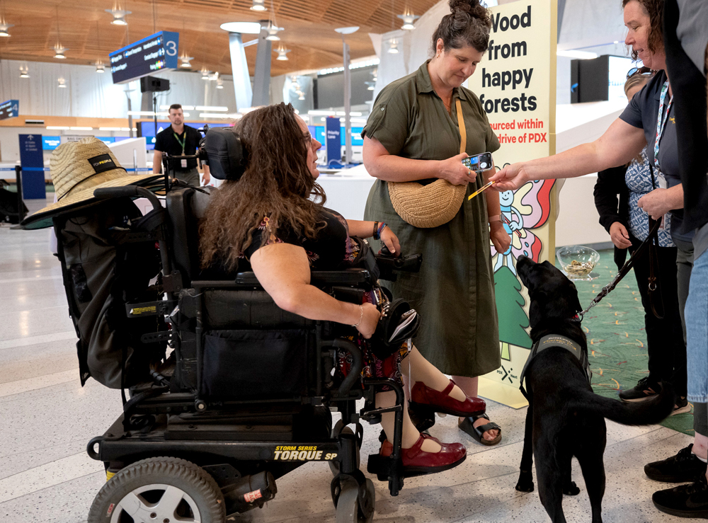 three Dove Lewis staff and two guests surround a Dove Lewis therapy dog at an event