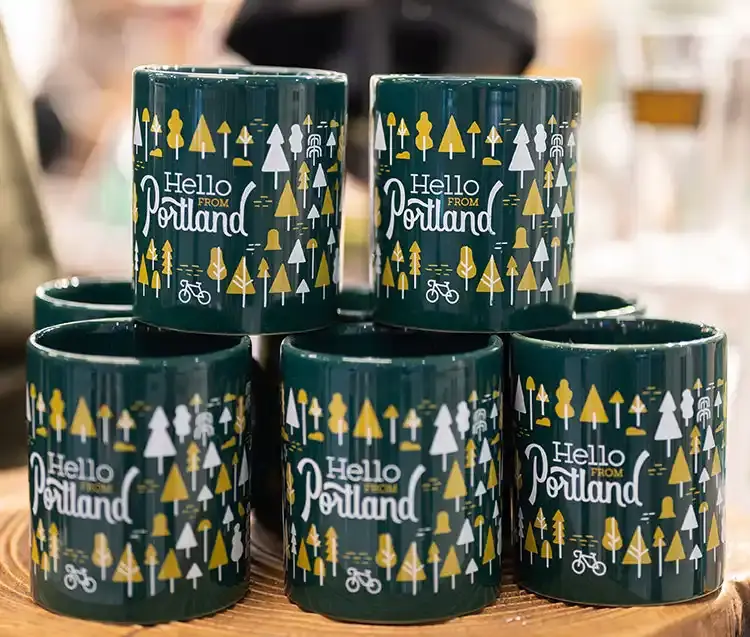 a stack of five coffee mugs that read hello from Portland