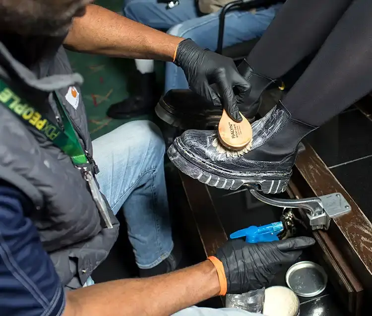a man performs a shoe shine on a pair of leather boots