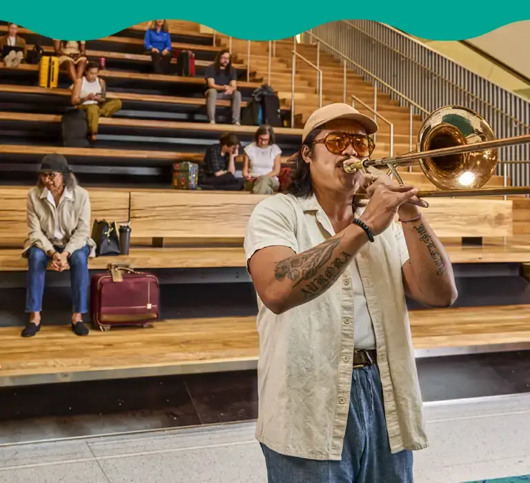 Man playing trumpet in front of stadium setting at PDX