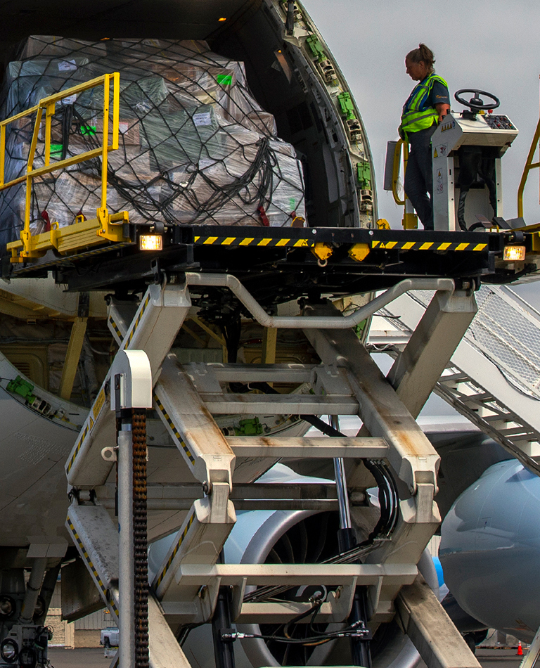 woman on scissor lift finishing loading cargo into front of plane