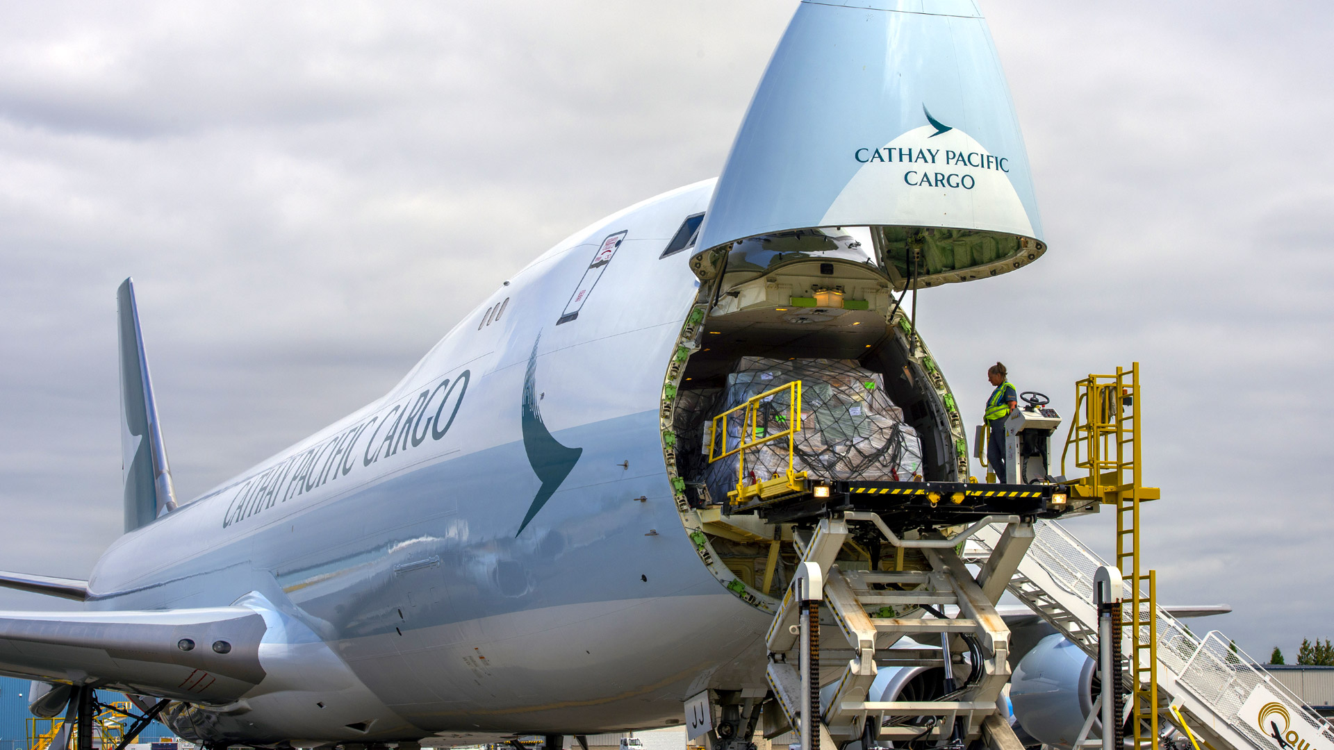 woman on scissor lift finishing loading cargo into front of plane