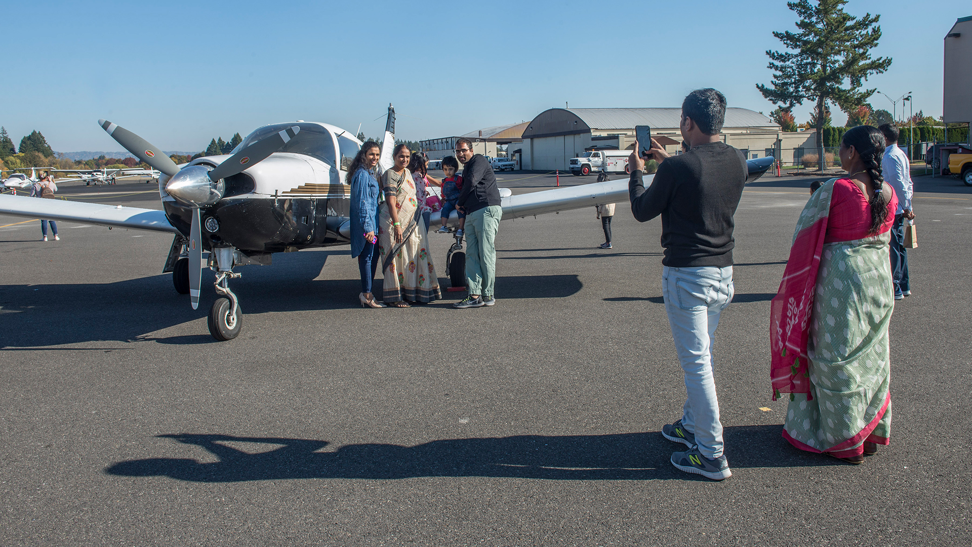 Family of South Asian heritage posing in front of small plane