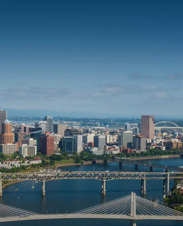 Aerial of downtown Portland on sunny day shows bridges over Willamette river