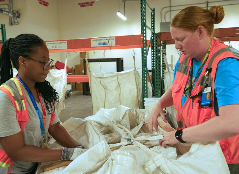 PSU interns tying up a large waste sack together