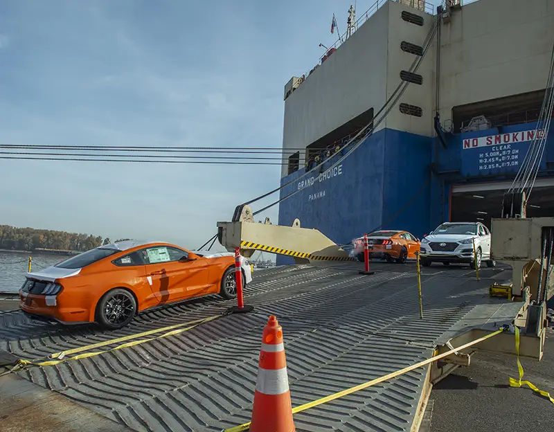 An orange sports car is driven onto a vessel