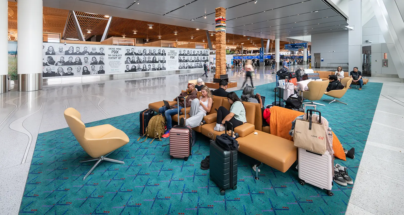 various passengers relax on the soft seating in a new original carpet zone in the ticket hall with their luggage in tow