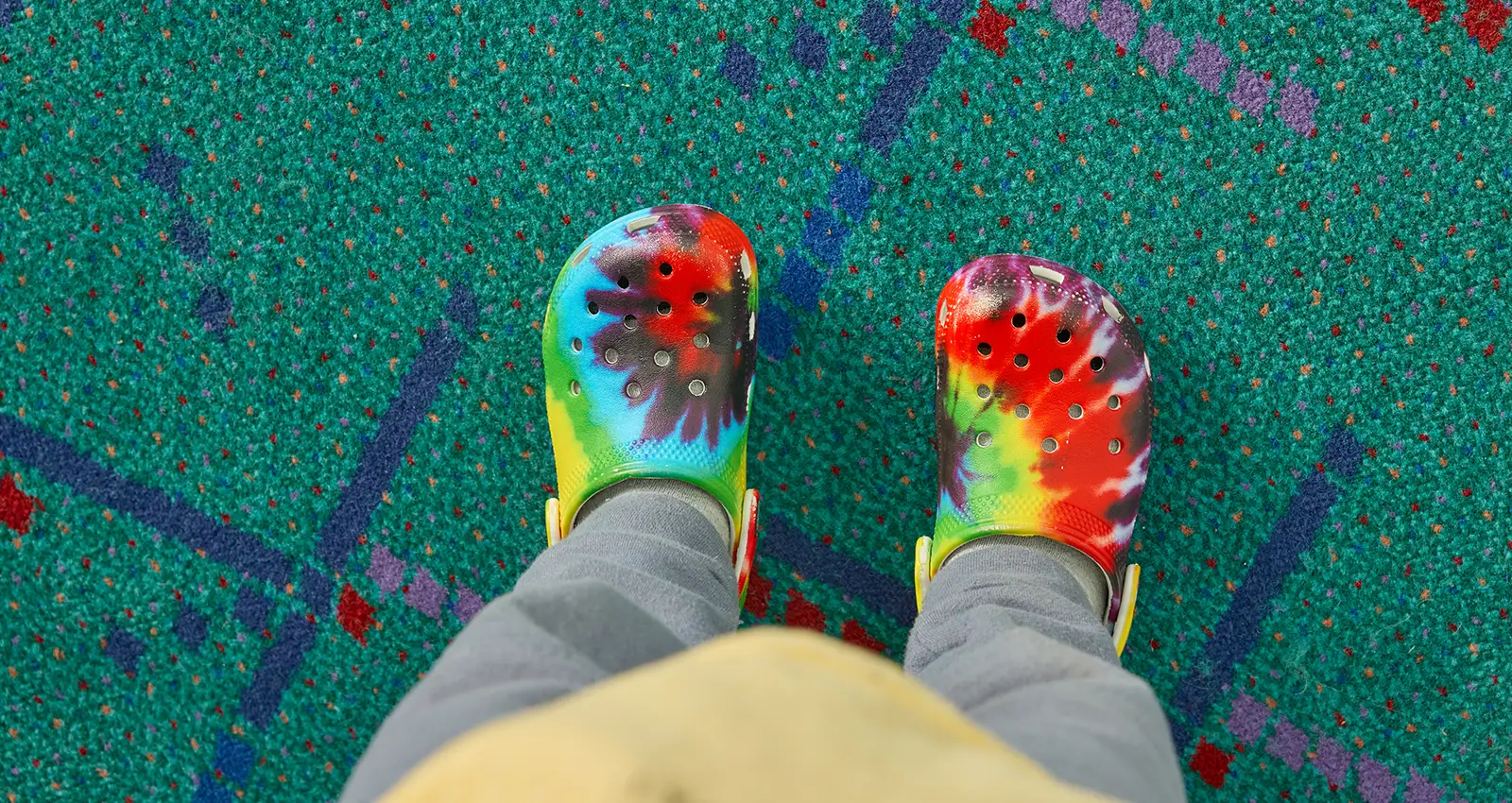 the shoe selfie of an individual wearing tie dye crocs