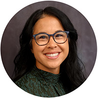 Emily has brown hair and is wearing glasses in her headshot