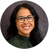 Emily has brown hair and is wearing glasses in her headshot