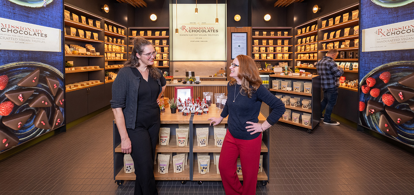 Melissa and Josie smiling at each other in front of their store