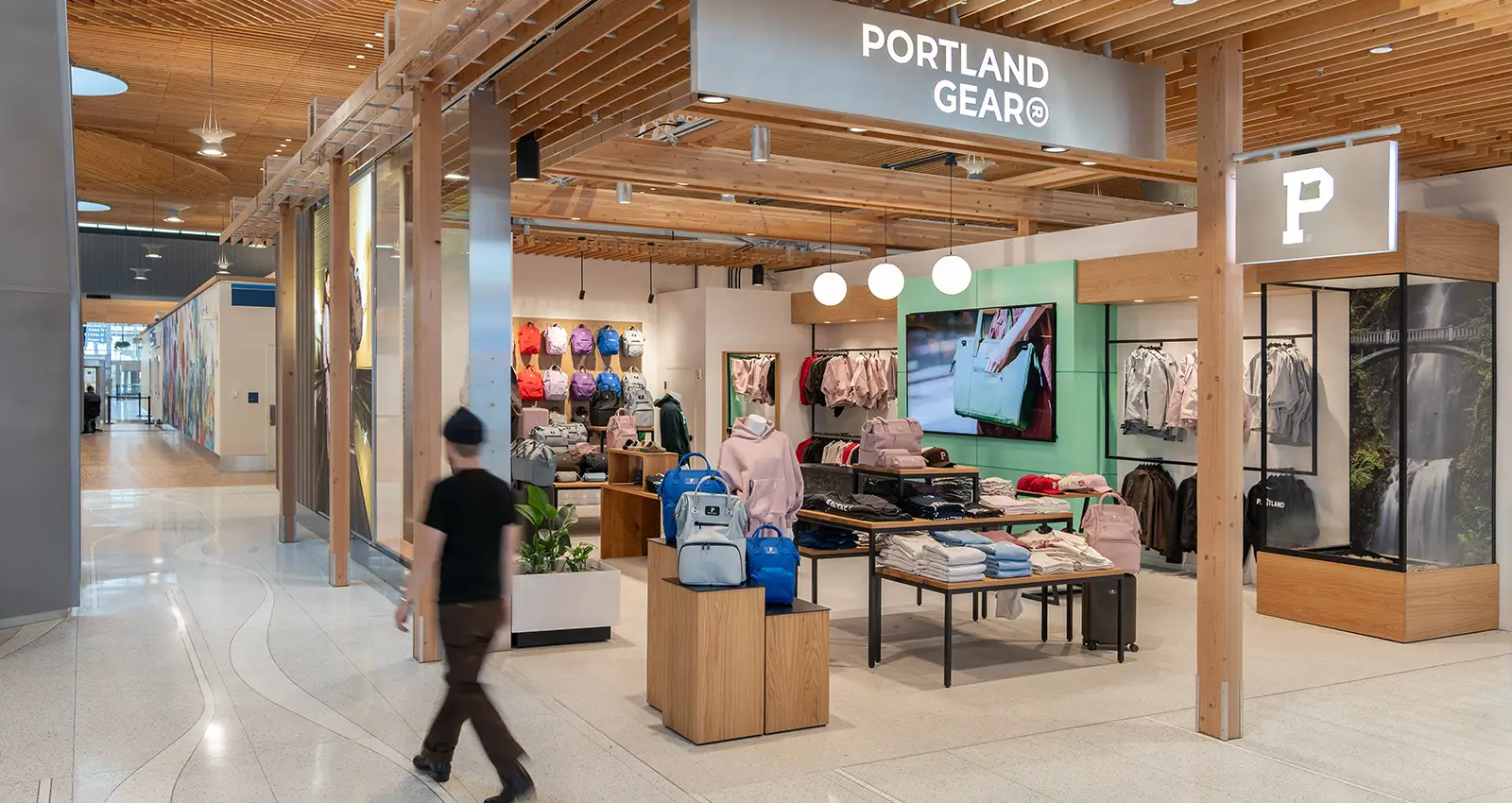a man walks past a wide shot of the colorful Portland Gear storefront, featuring backpacks and clothing