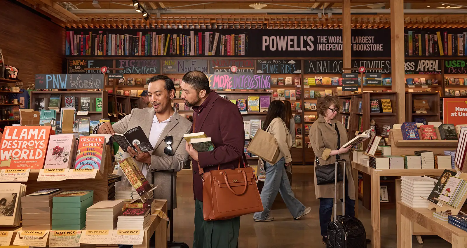 two Filipino men are shopping with one man showing the other a book he found while smiling