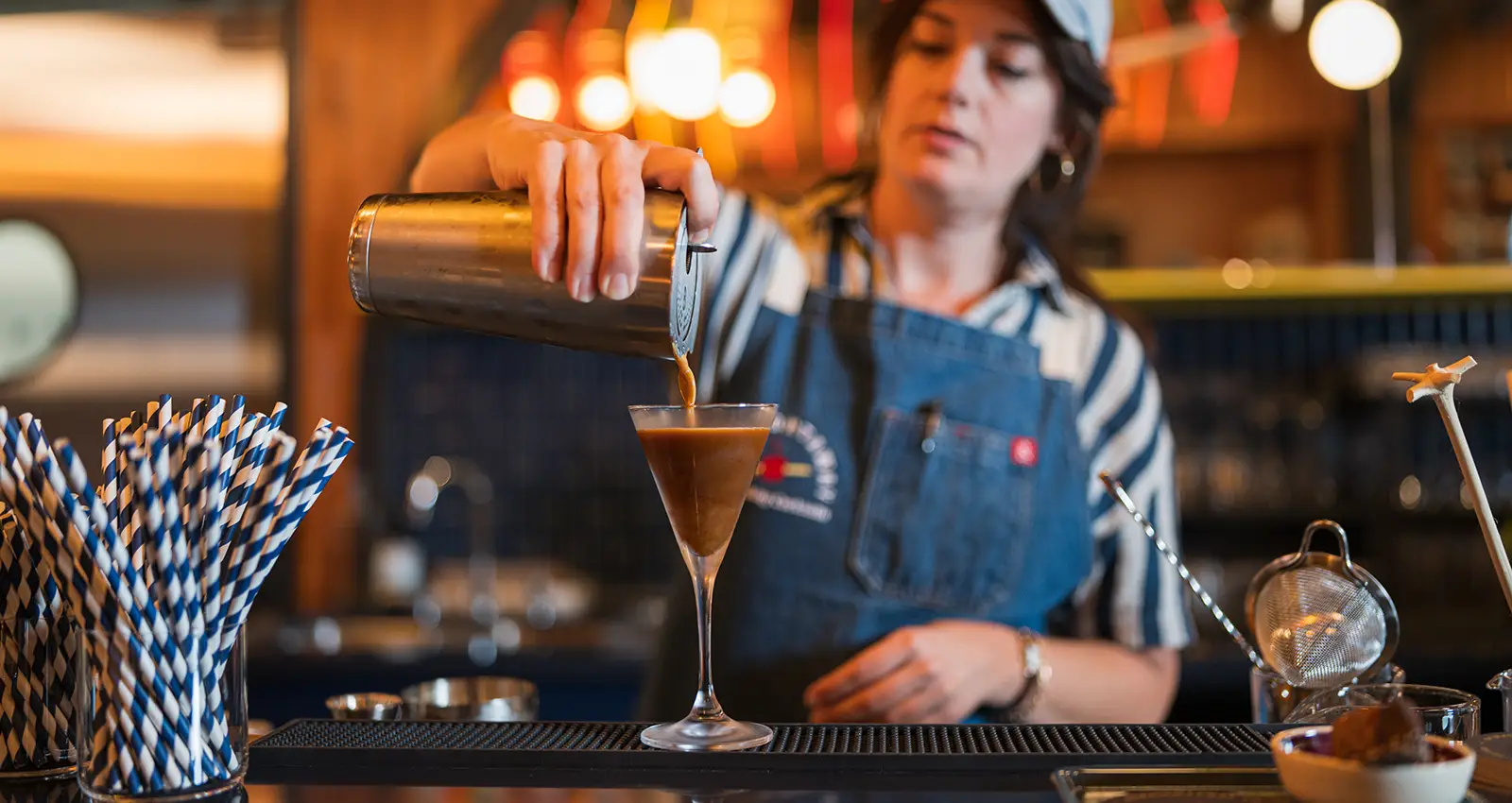 a Straightaway bartender is slightly out of focus while pouring an ice cold espresso martini in the foreground
