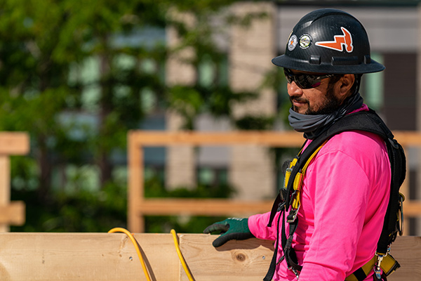 man in hardhat and harness working on timber building