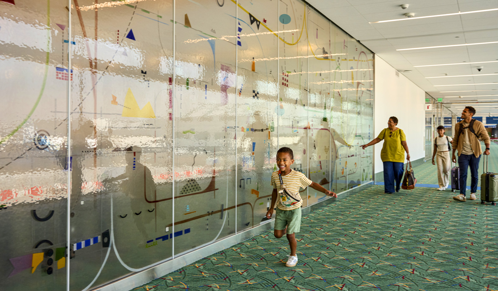 A child runs through the glass wall art named Between by artist Yoonhee Choi at Portland International Airport